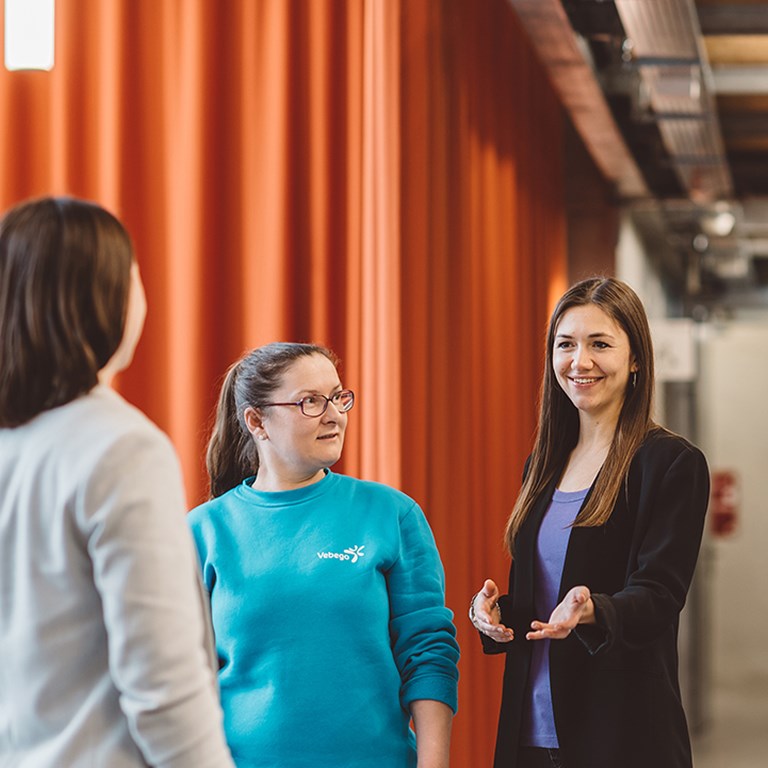 drei Damen diskutieren in einem Bürogebäude über etwas