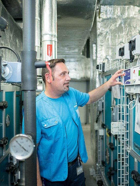 männlicher technischer Hausmeister vor einer technischen Anlage